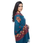 Detail of orange and red Aari embroidery on teal wool fabric